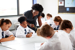 Adobestock 234479406 Teacher Bends To Speak With Pupil In A Classroom